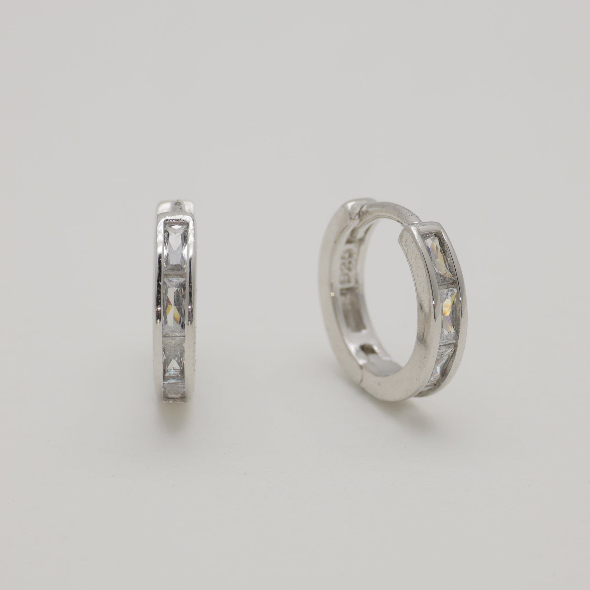 Two silver hoop earrings on a light gray background