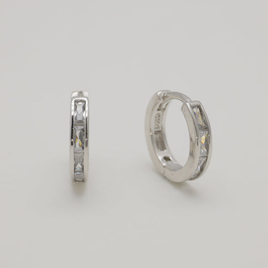 Two silver hoop earrings on a light gray background
