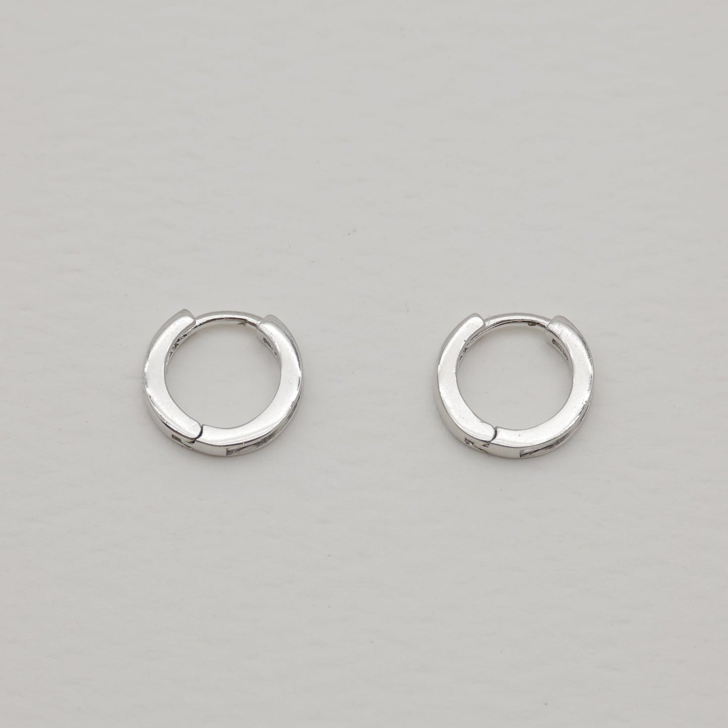 Pair of silver hoop earrings on a light gray background