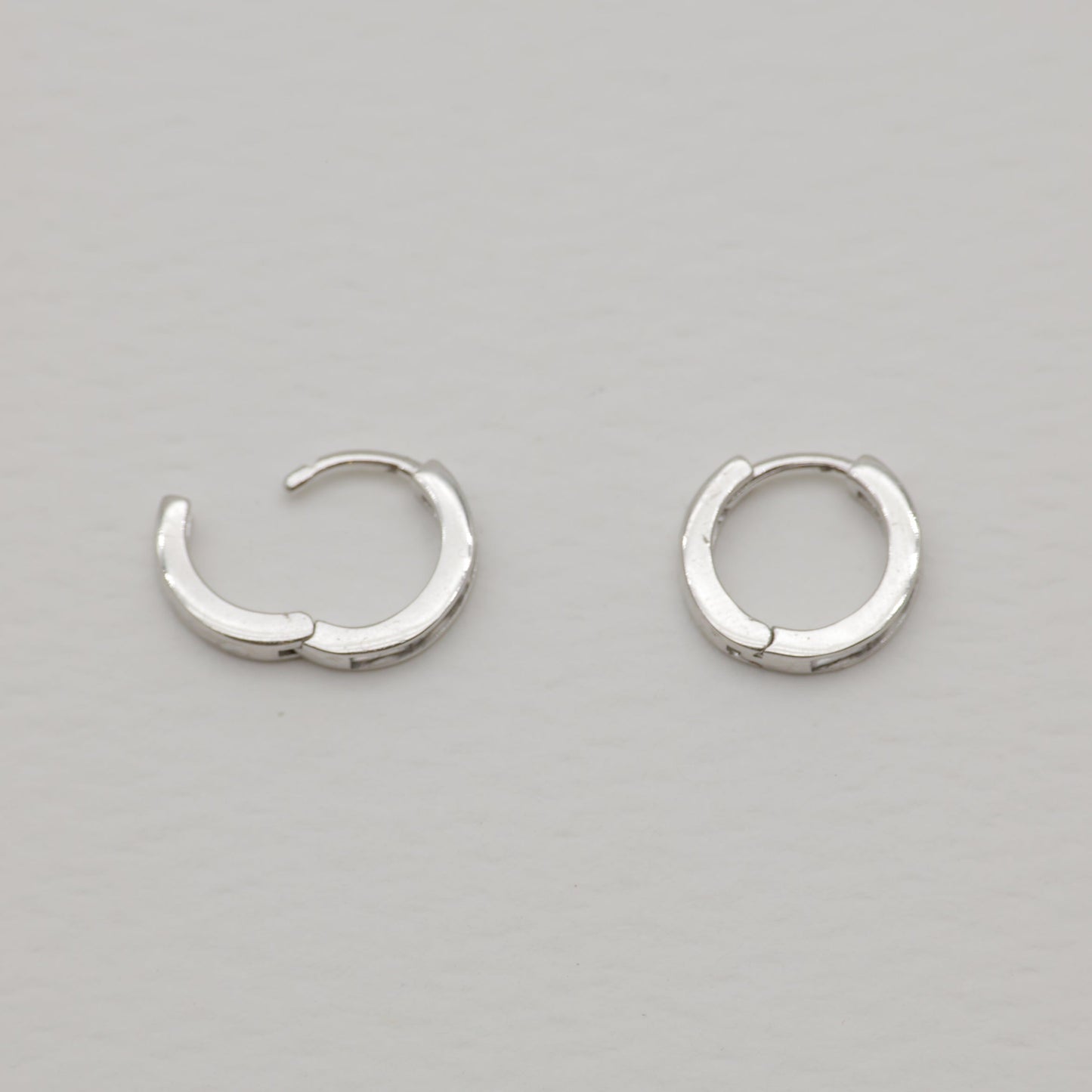 Pair of silver hoop earrings on a gray background