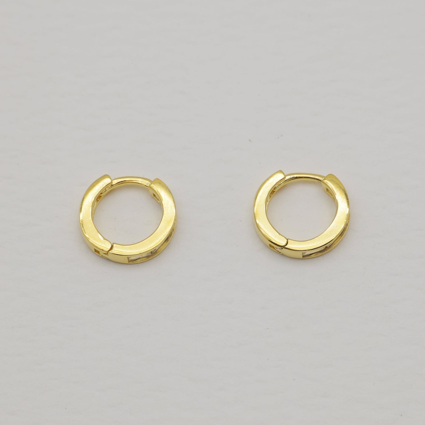 Pair of gold hoop earrings on a light gray background