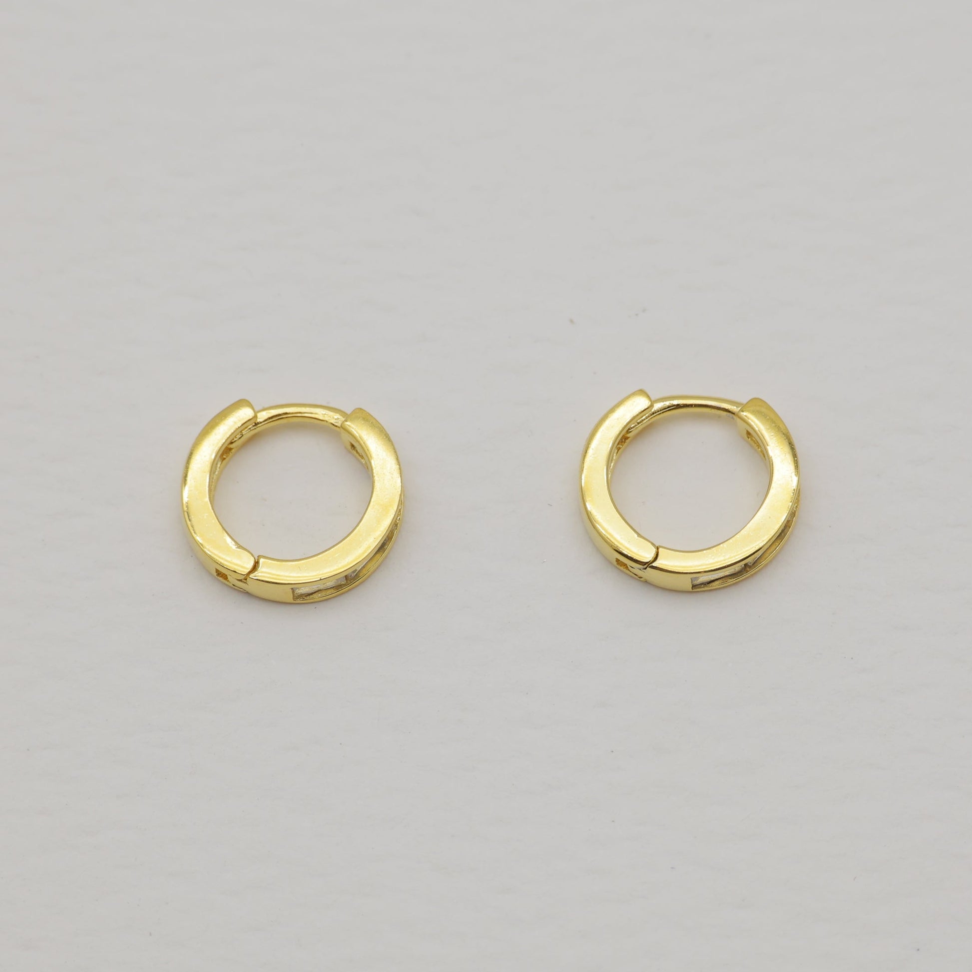 Pair of gold hoop earrings on a light gray background
