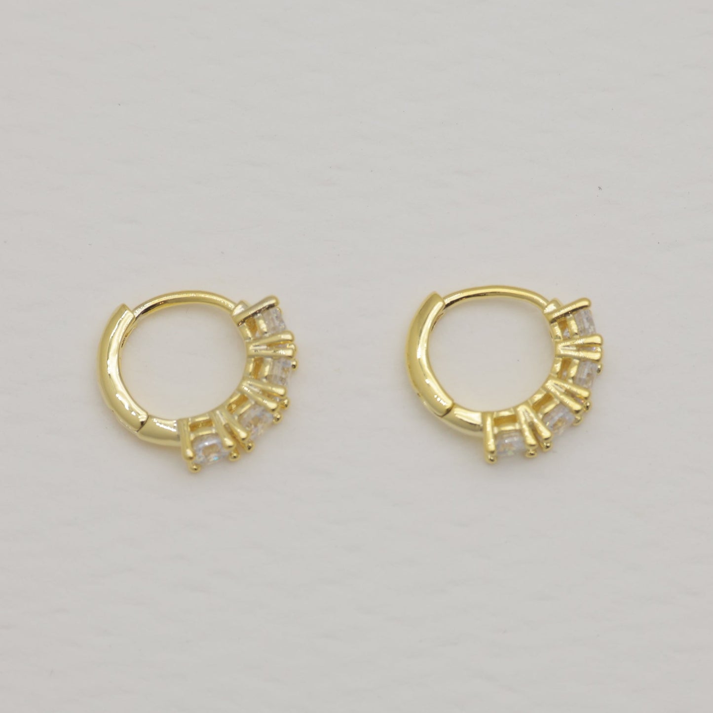 Pair of gold hoop earrings on a light gray background