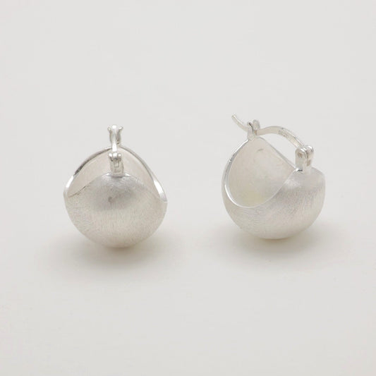 Matte sculpted hoop earrings in sterling silver on neutral background, front angle