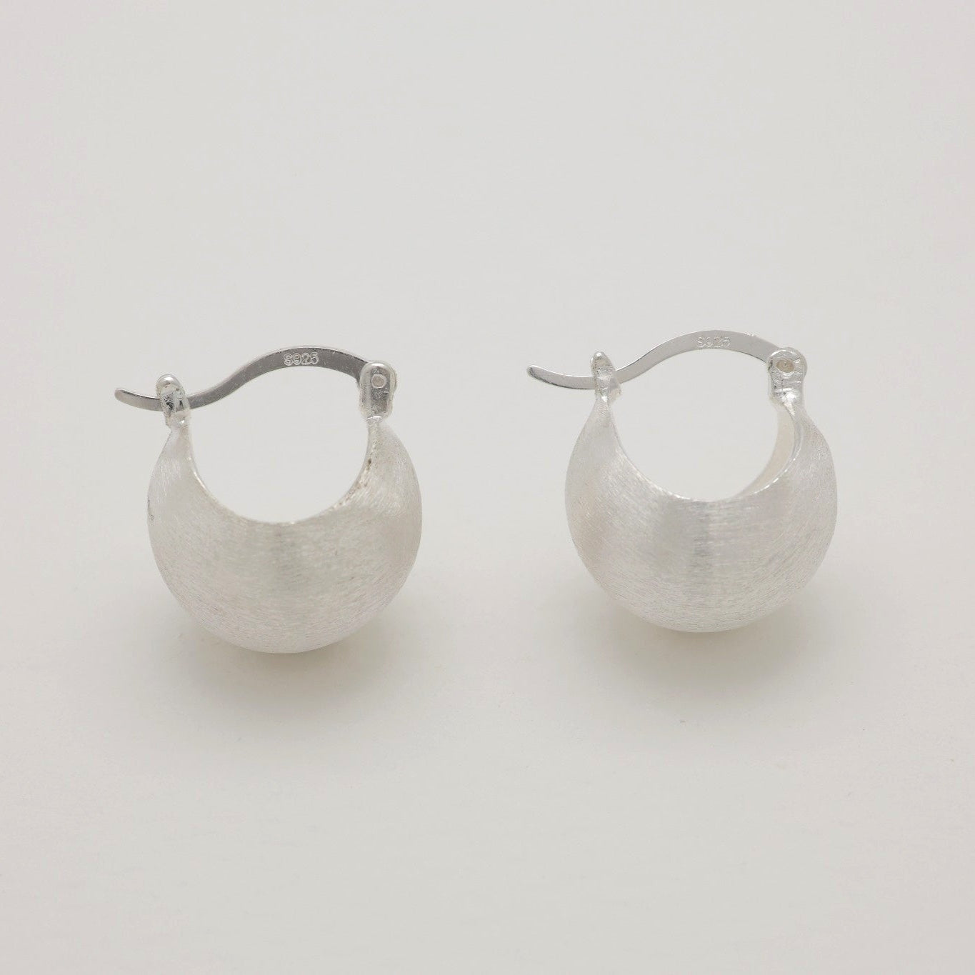 “Sterling silver sculpted hoop earrings showing latch-back closure detail.”
