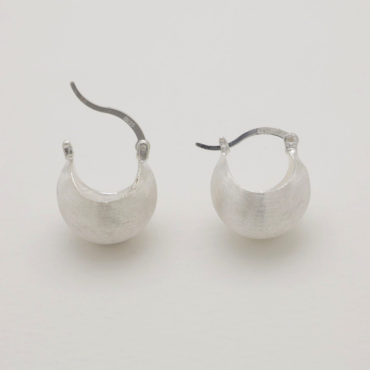 “Matte brushed sterling silver hoop earrings with curved dome form, open clasp view.”