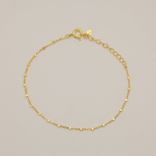 Gold bracelet on a light gray background