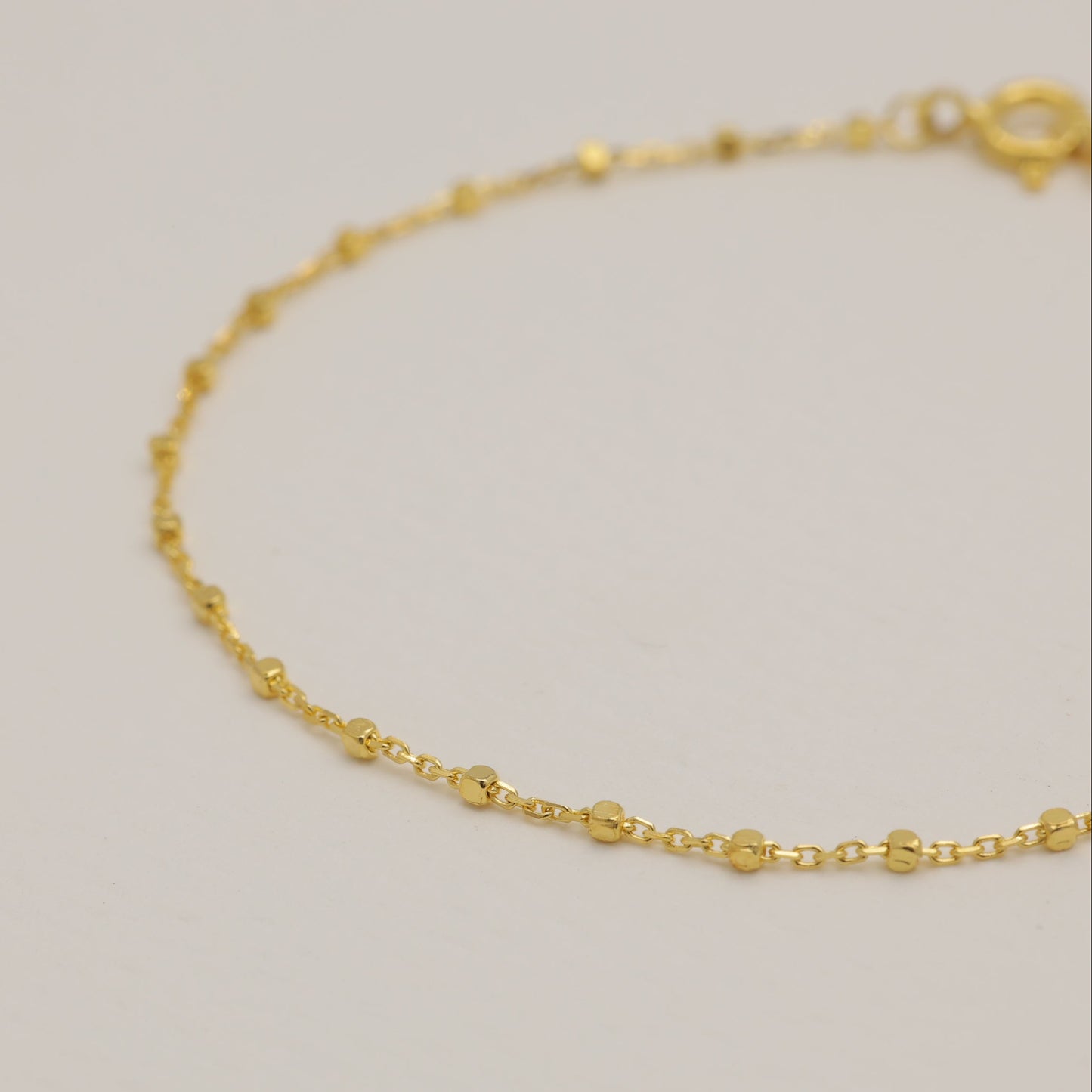 Gold bracelet on a light gray background