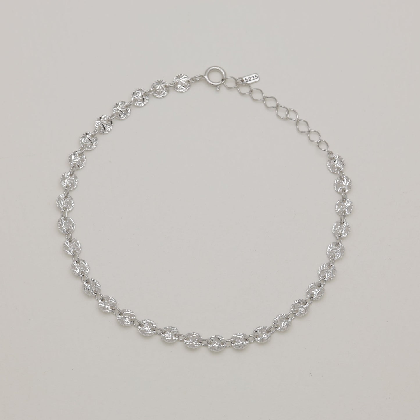 Silver chain bracelet on a light gray background