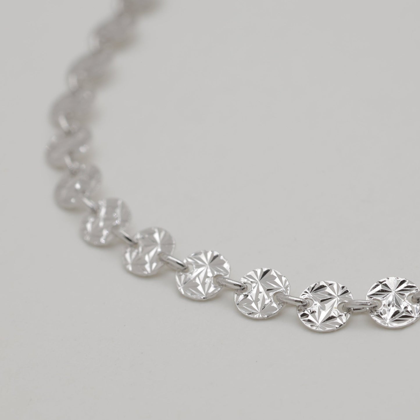 Silver necklace with round diamonds on a light gray background
