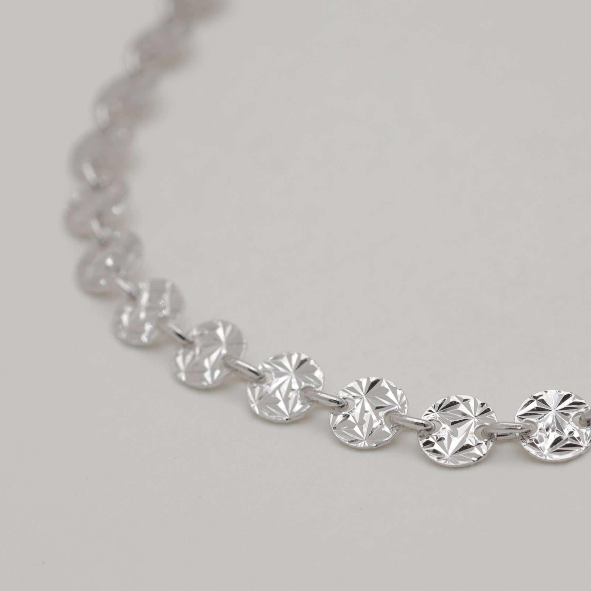 Silver necklace with round diamonds on a light gray background