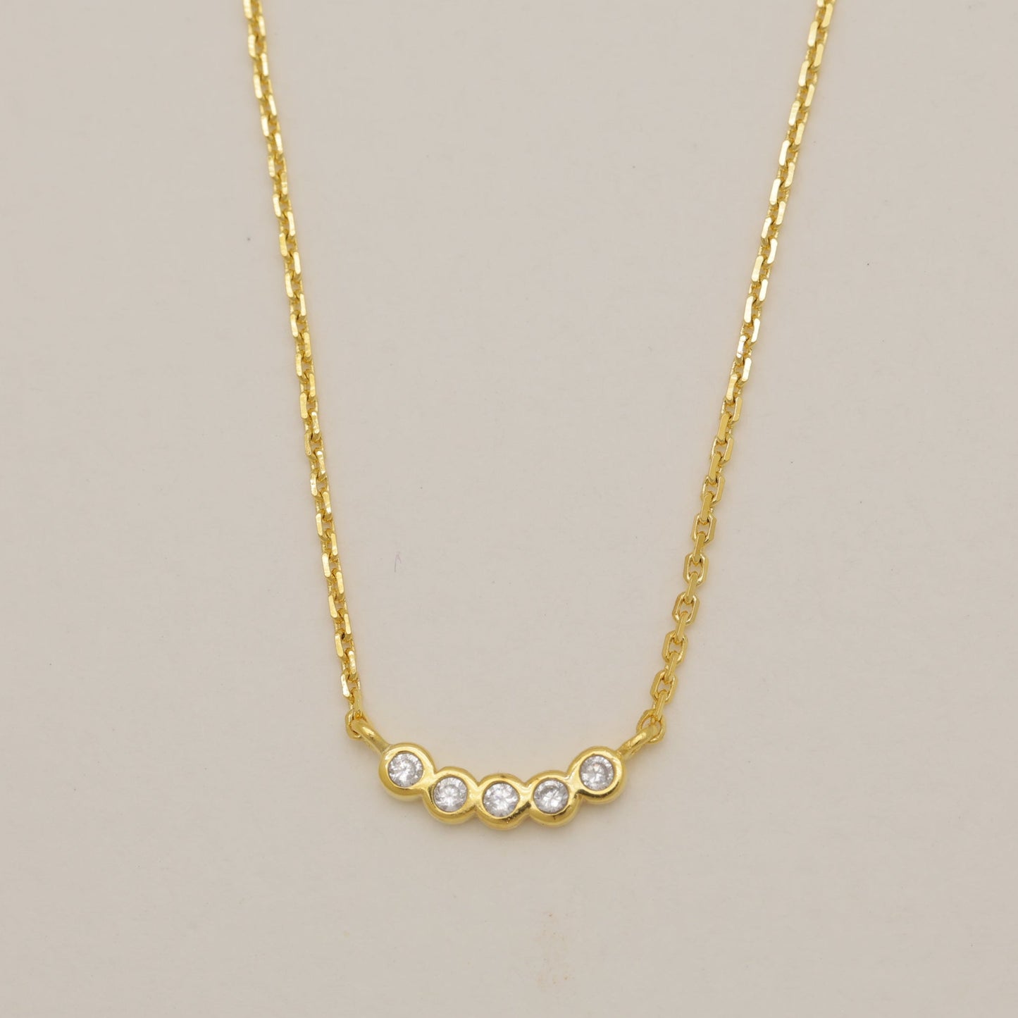 Gold necklace with small diamonds on a beige background
