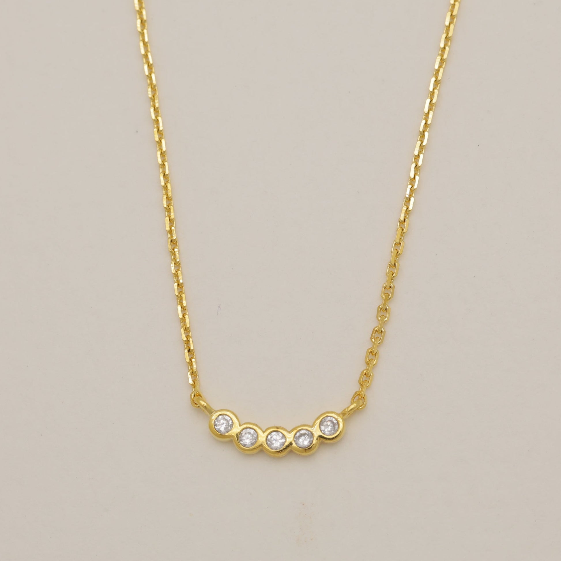 Gold necklace with small diamonds on a beige background