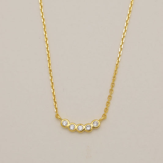 Gold necklace with small diamonds on a beige background