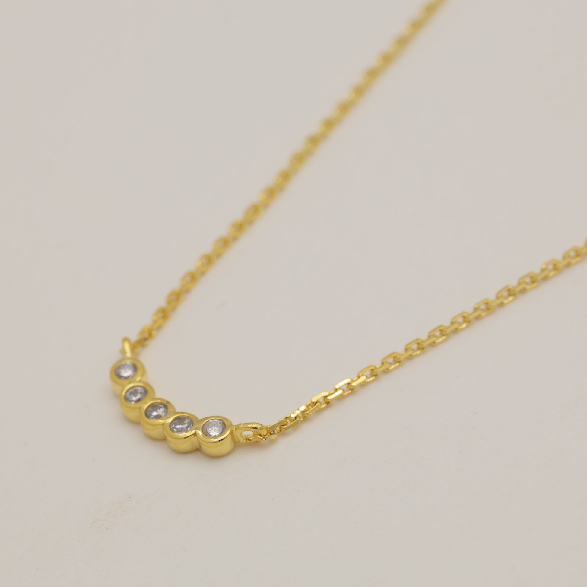 Gold necklace with small diamonds on a beige background