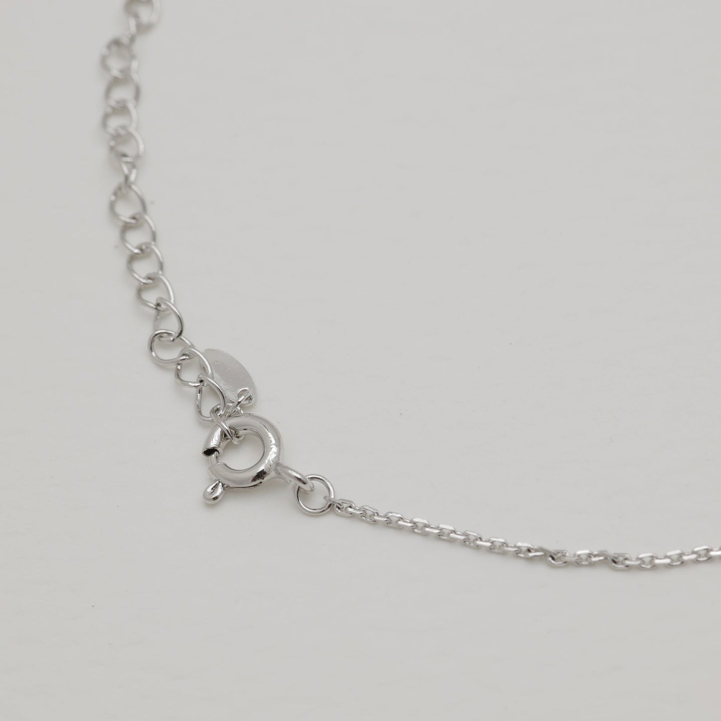 Silver necklace with a clasp on a light gray background