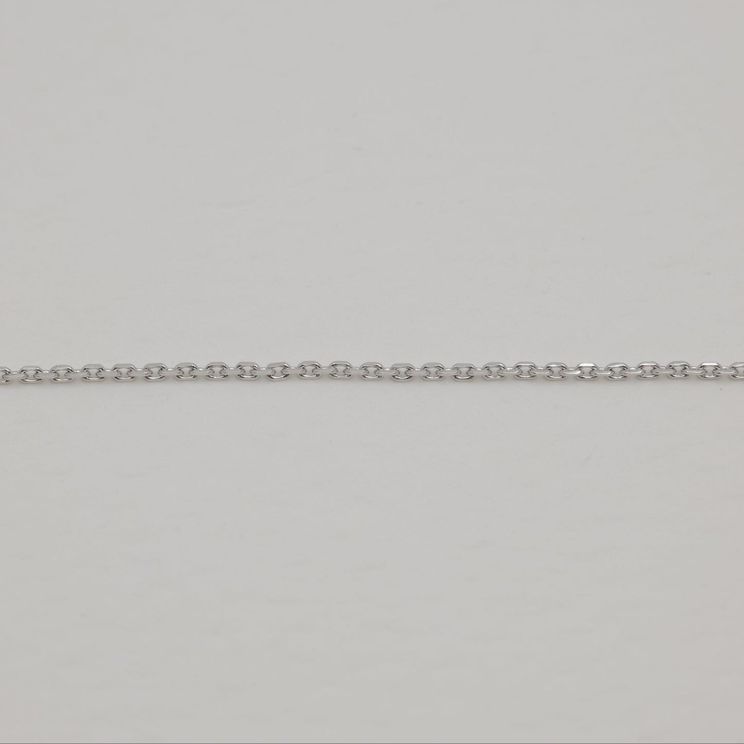 Close-up of a silver chain on a light gray background