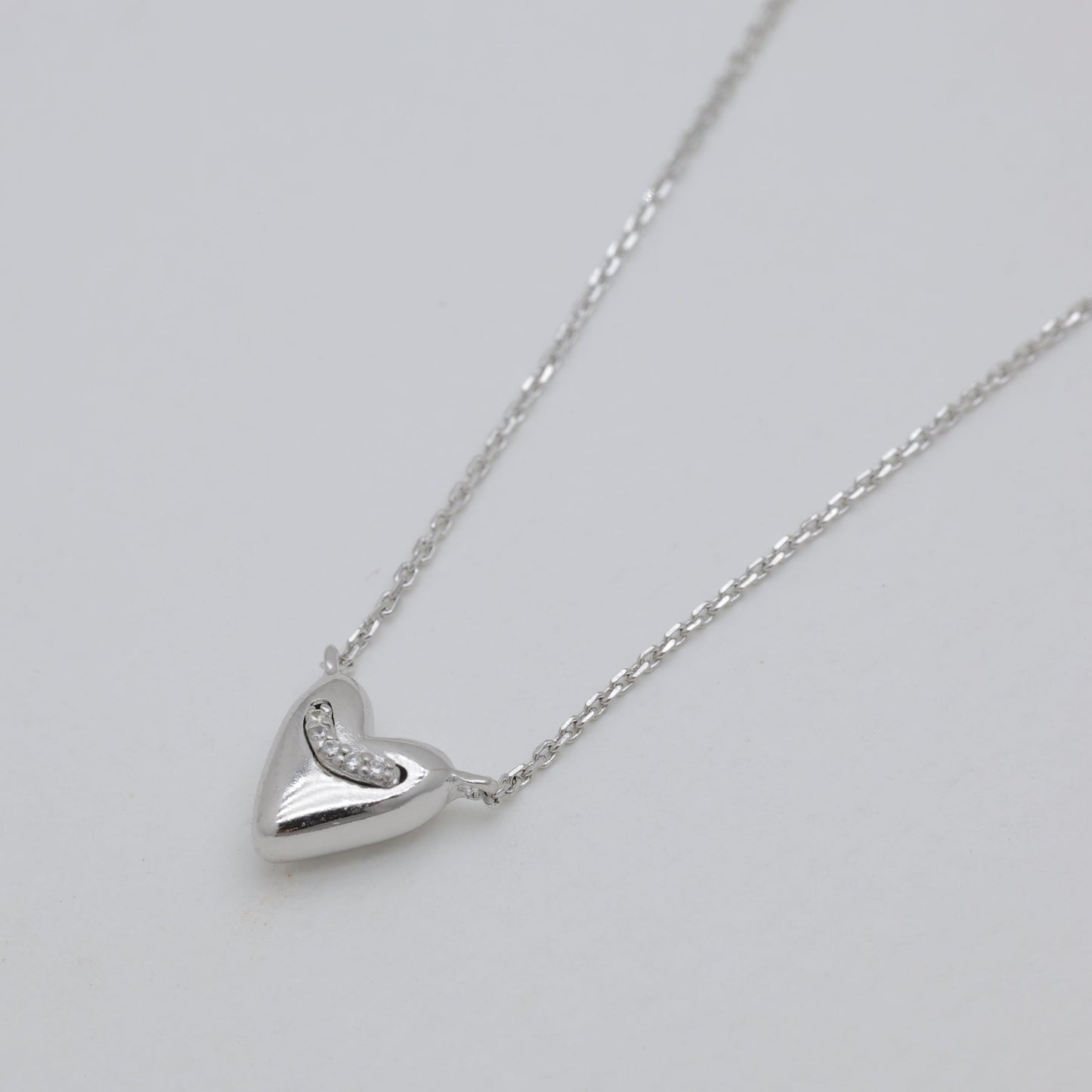 Silver heart-shaped pendant necklace on a light gray background