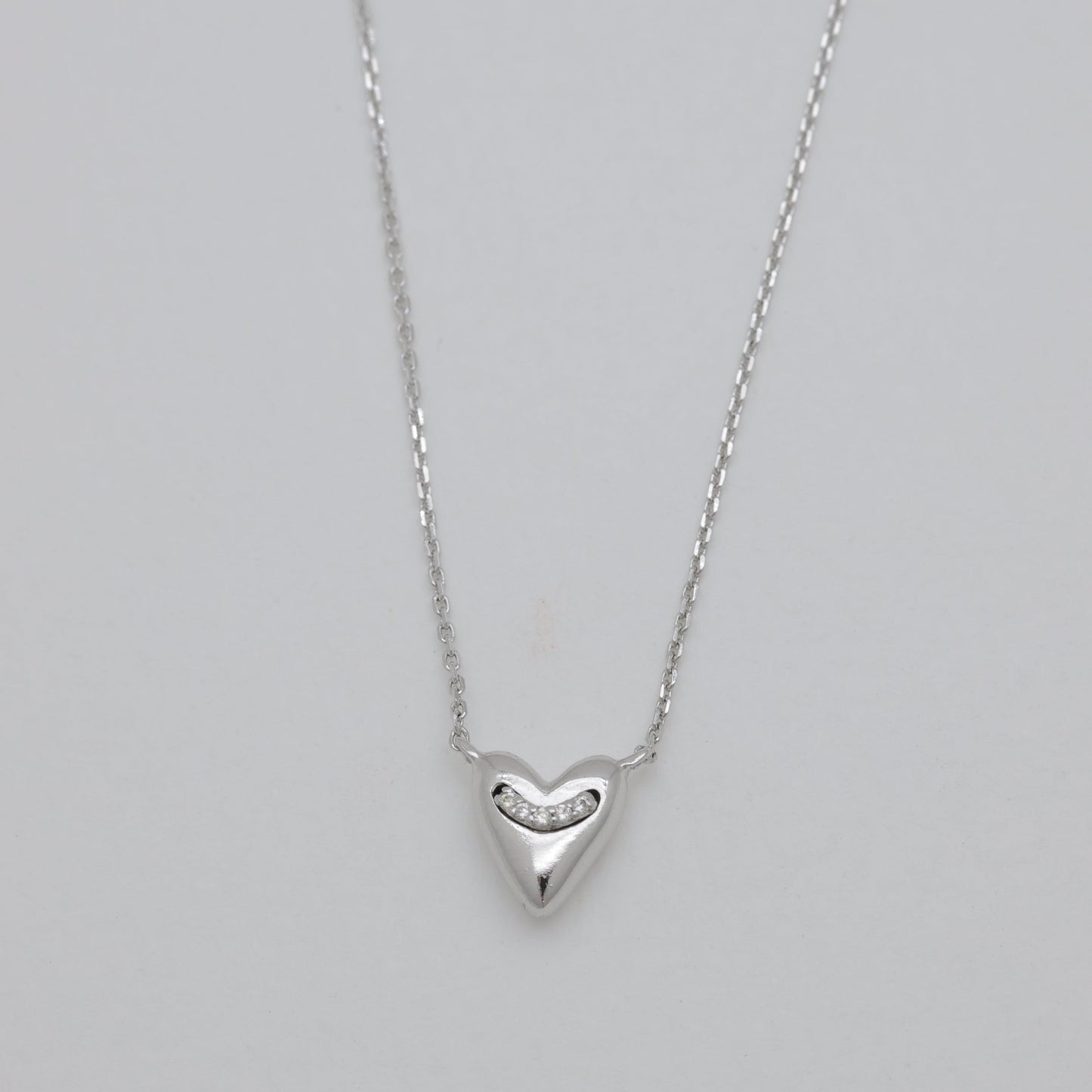 Silver heart-shaped pendant necklace on a gray background