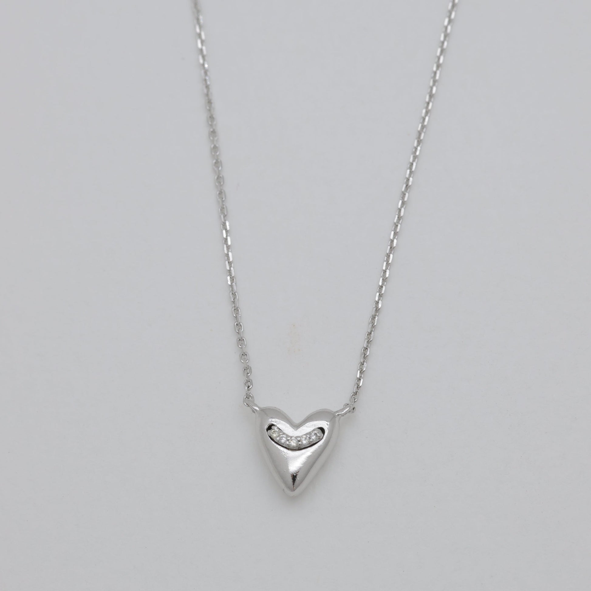 Silver heart-shaped pendant necklace on a gray background