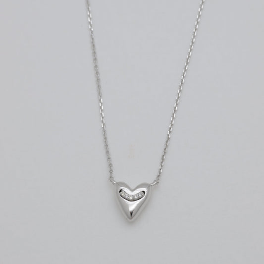 Silver heart-shaped pendant necklace on a gray background