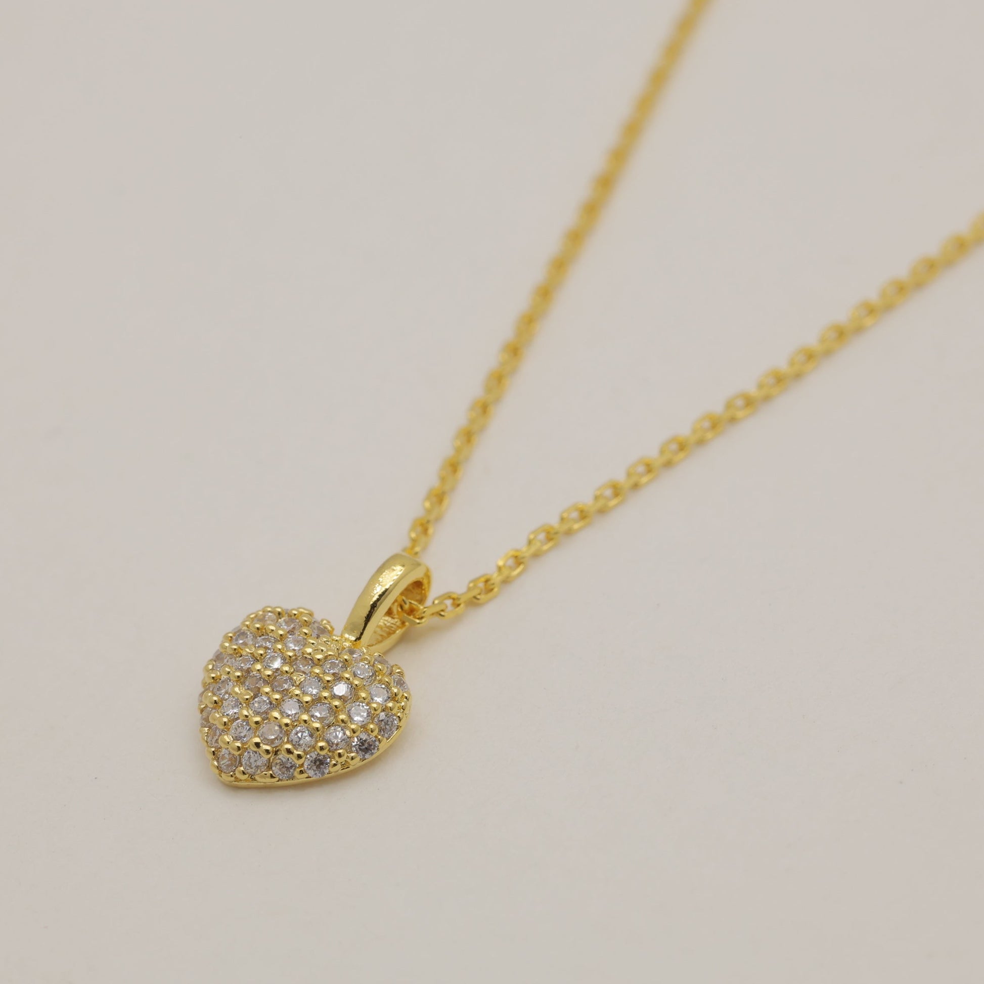 Gold heart-shaped pendant necklace on a beige background