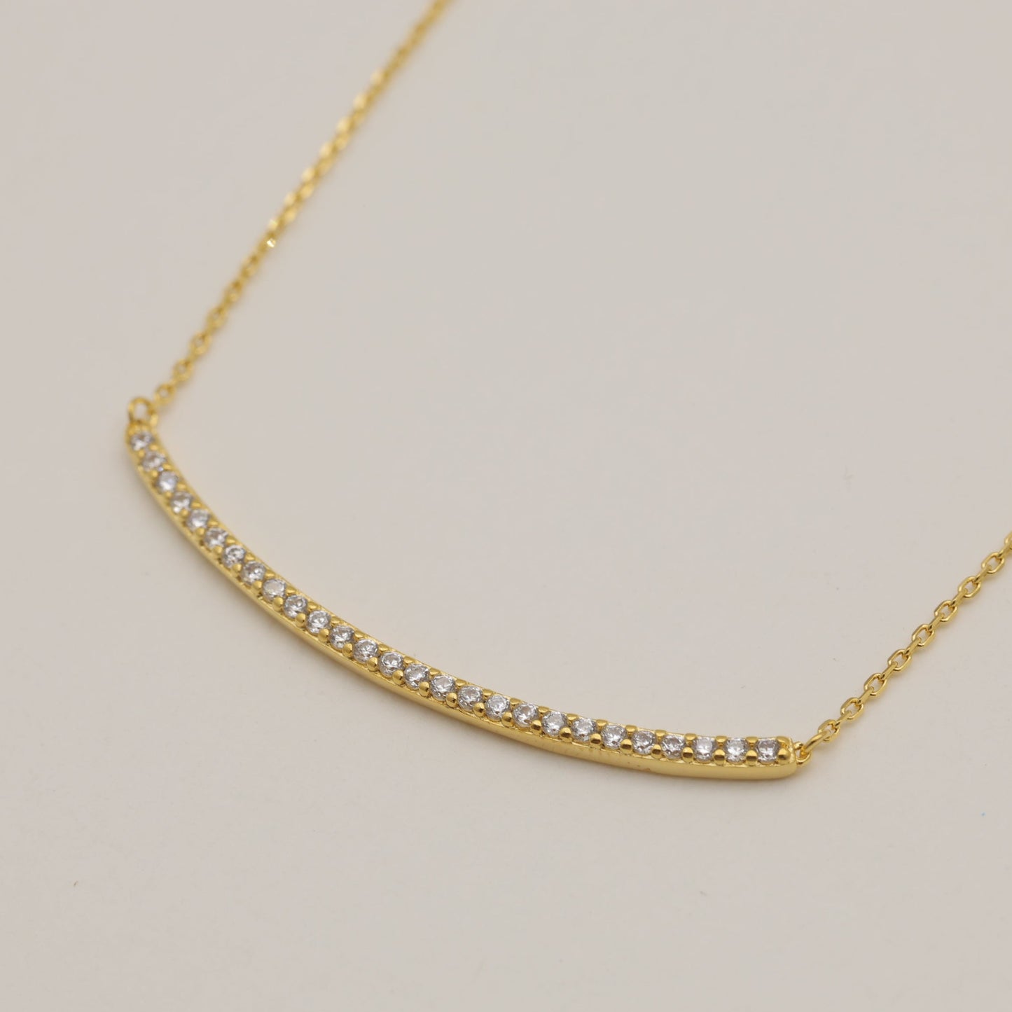Gold necklace with small diamonds on a light gray background