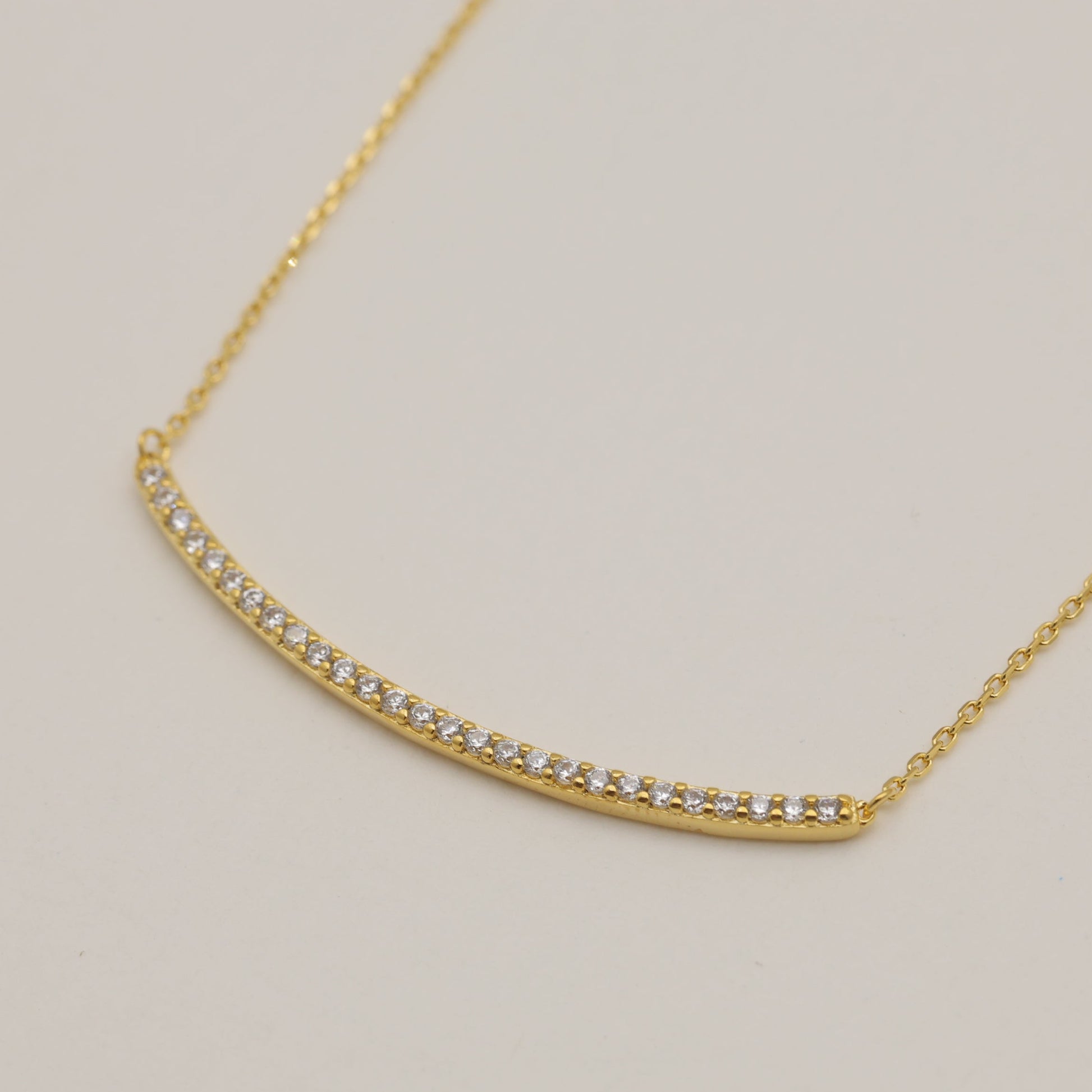 Gold necklace with small diamonds on a light gray background