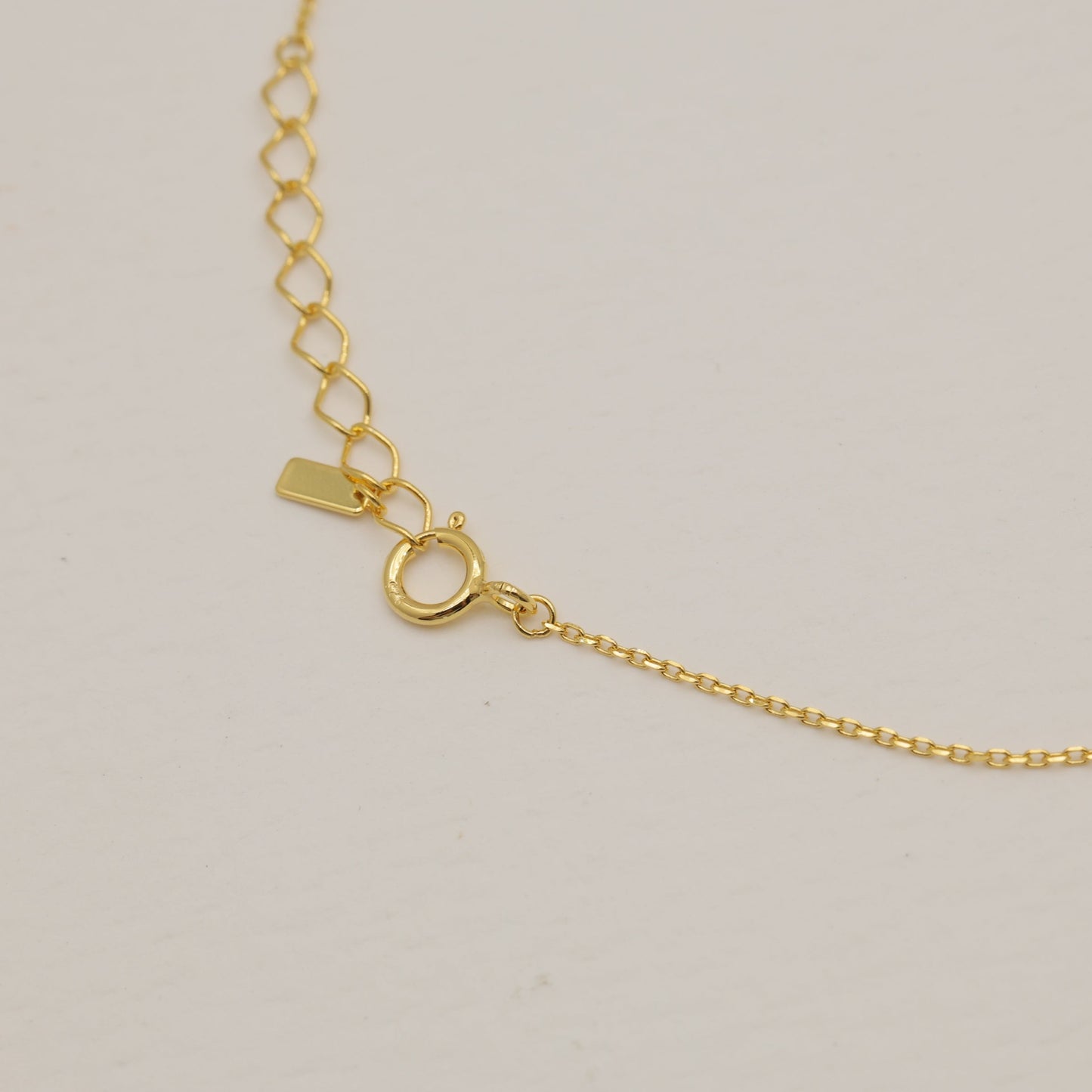 Gold necklace on a light beige background