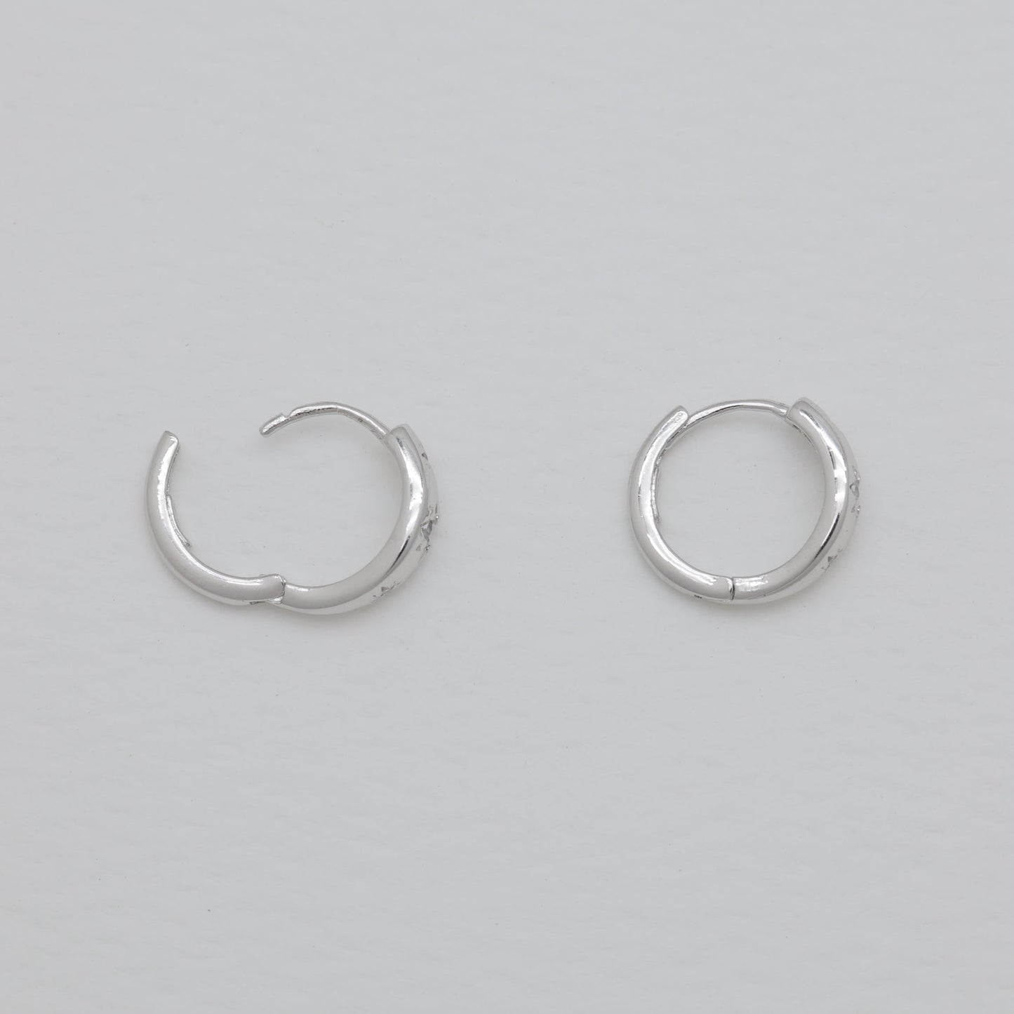 Pair of silver hoop earrings on a light gray background