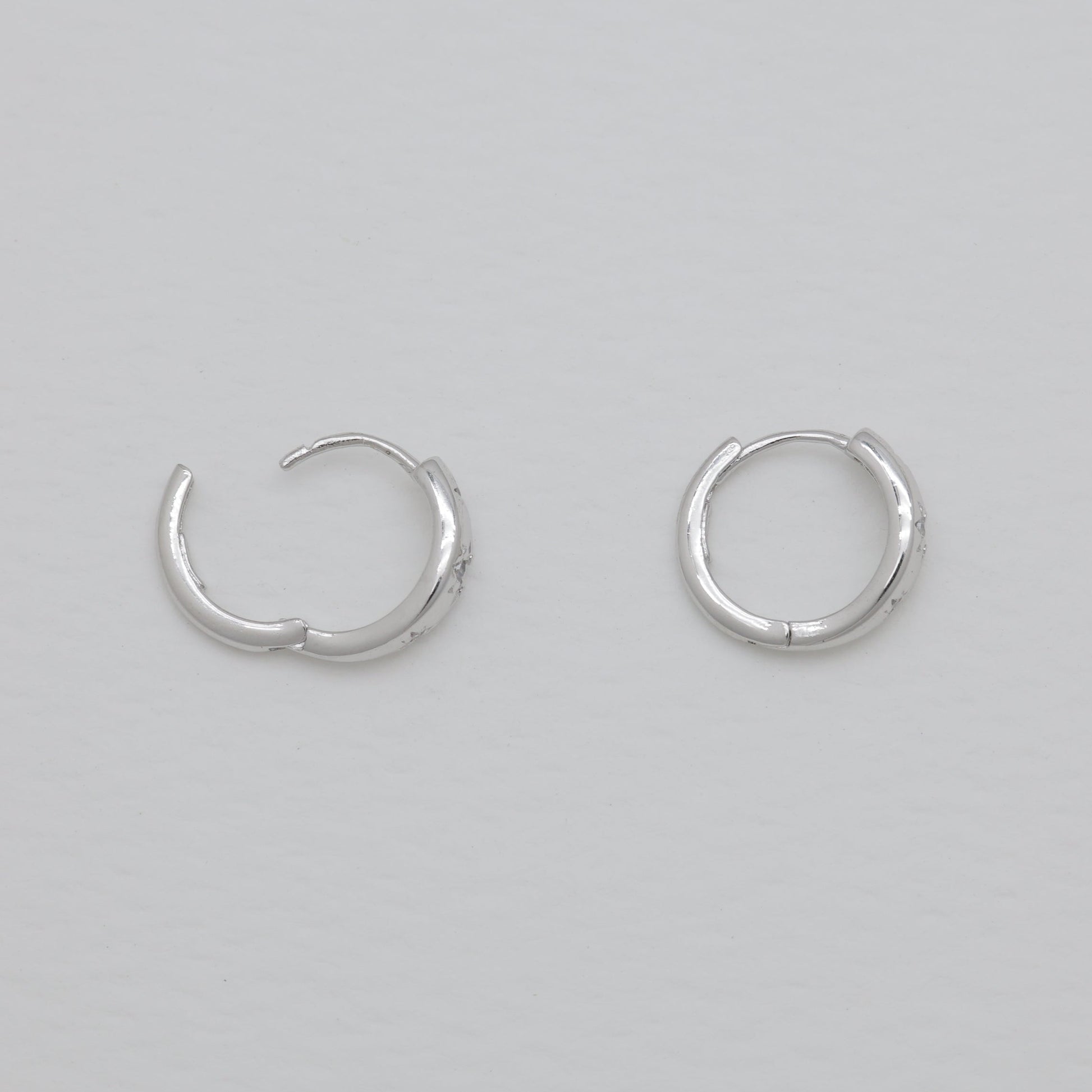 Pair of silver hoop earrings on a light gray background