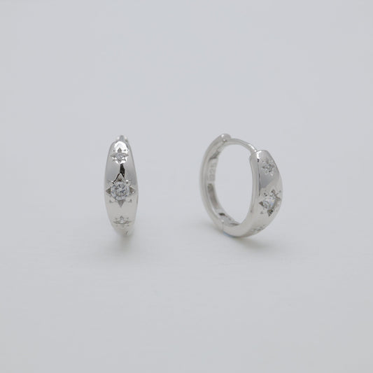 Two silver hoop earrings on a light gray background