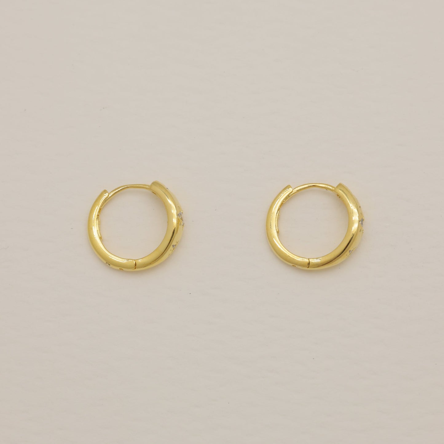 Pair of gold hoop earrings on a beige background