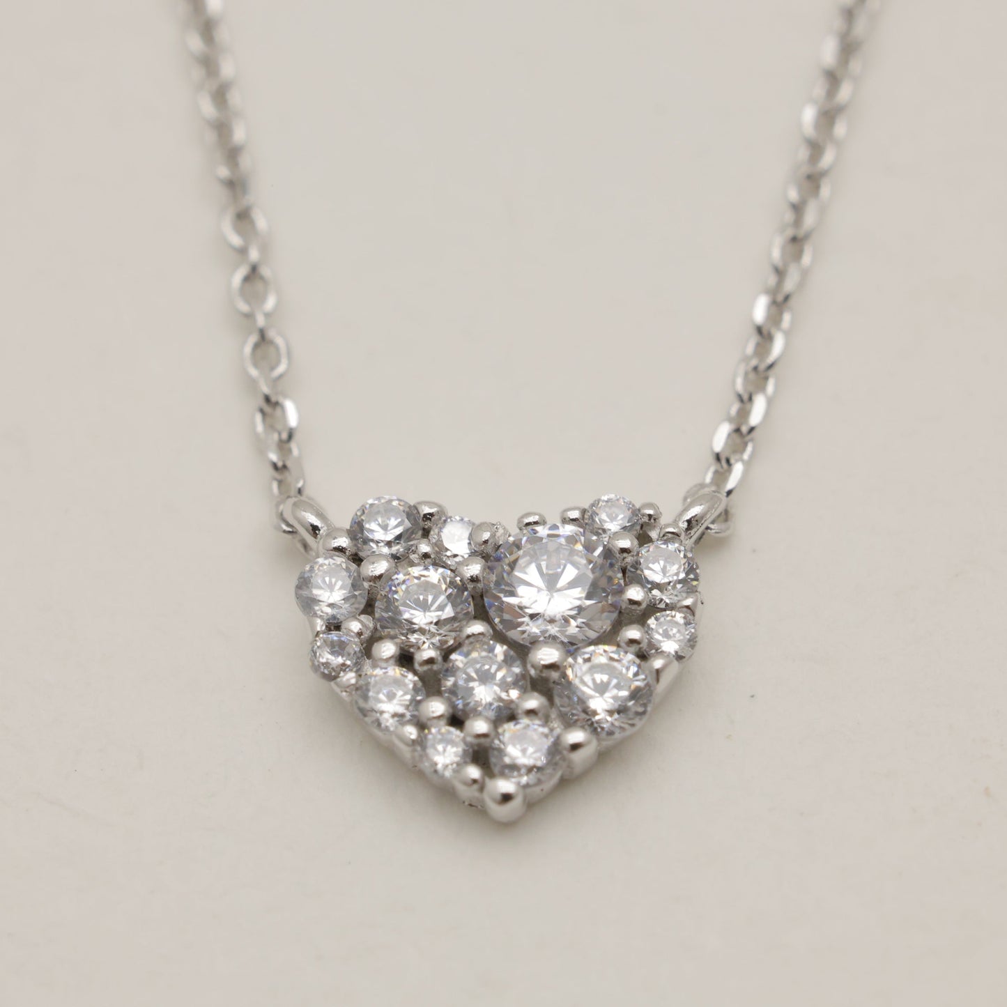Heart-shaped diamond necklace on a light gray background