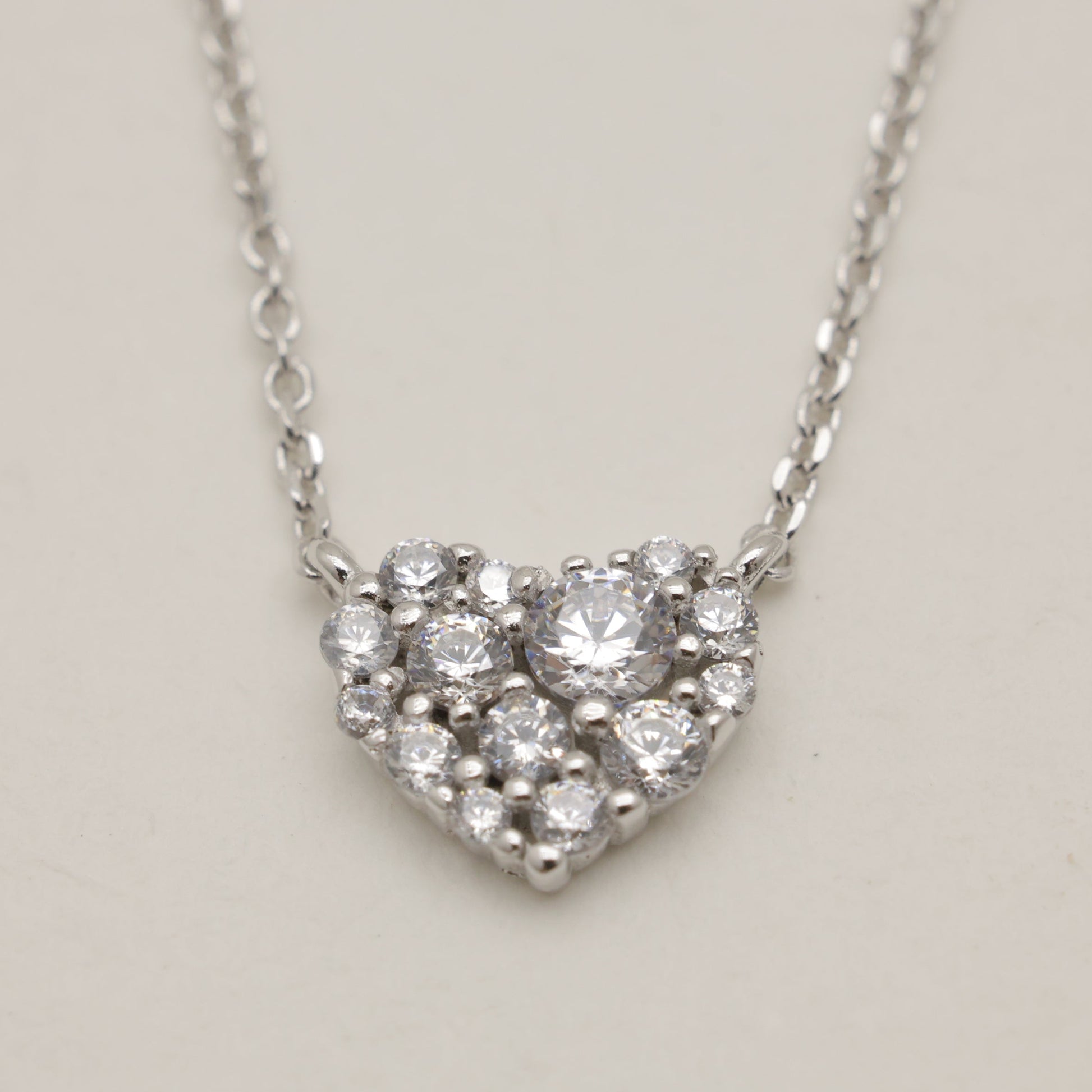 Heart-shaped diamond necklace on a light gray background