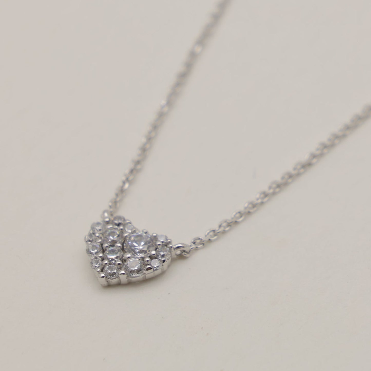 Heart-shaped diamond necklace on a light beige background