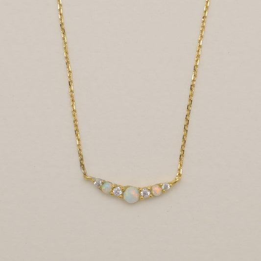 Gold necklace with small gemstones on a beige background