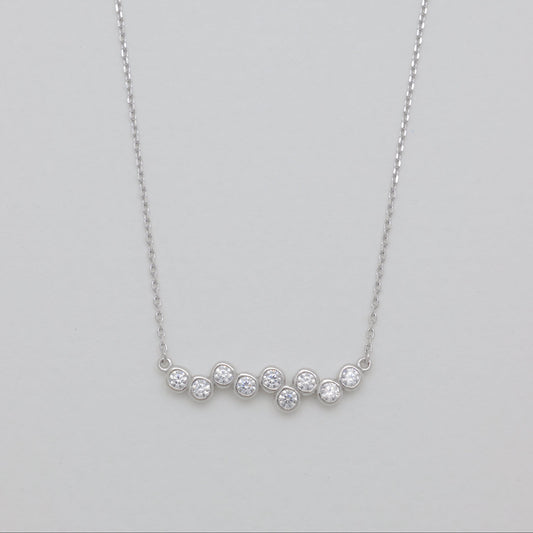 Silver necklace with small diamonds on a light gray background