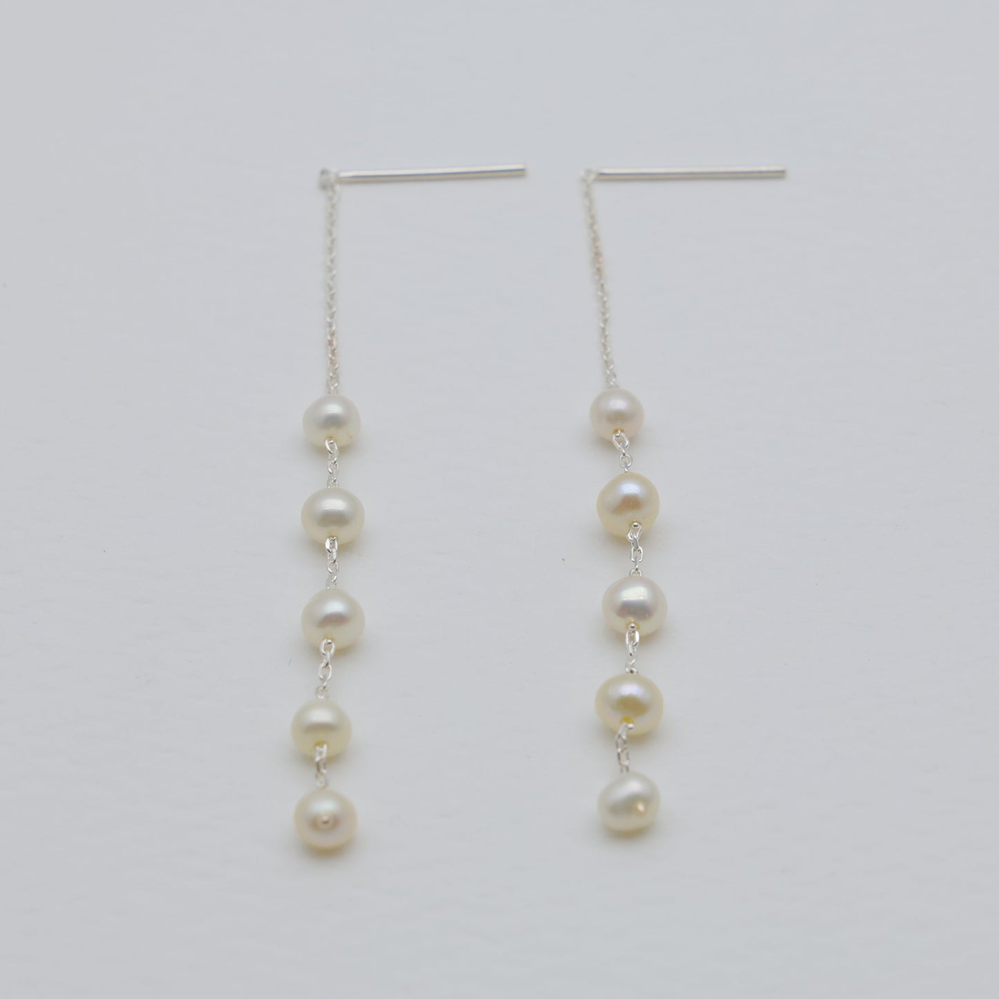 Pair of pearl drop earrings on a light gray background