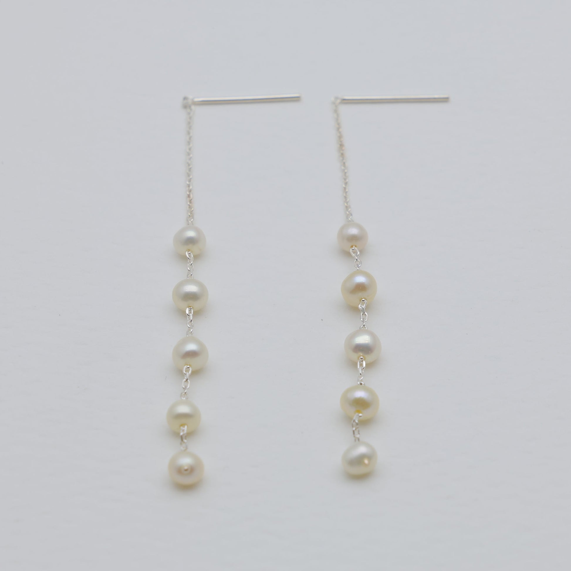 Pair of pearl drop earrings on a light gray background
