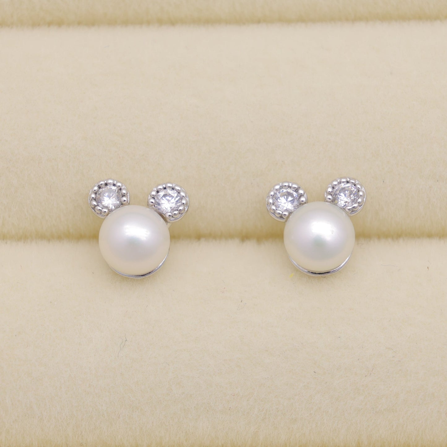 Pearl earrings with small crystals on a beige background
