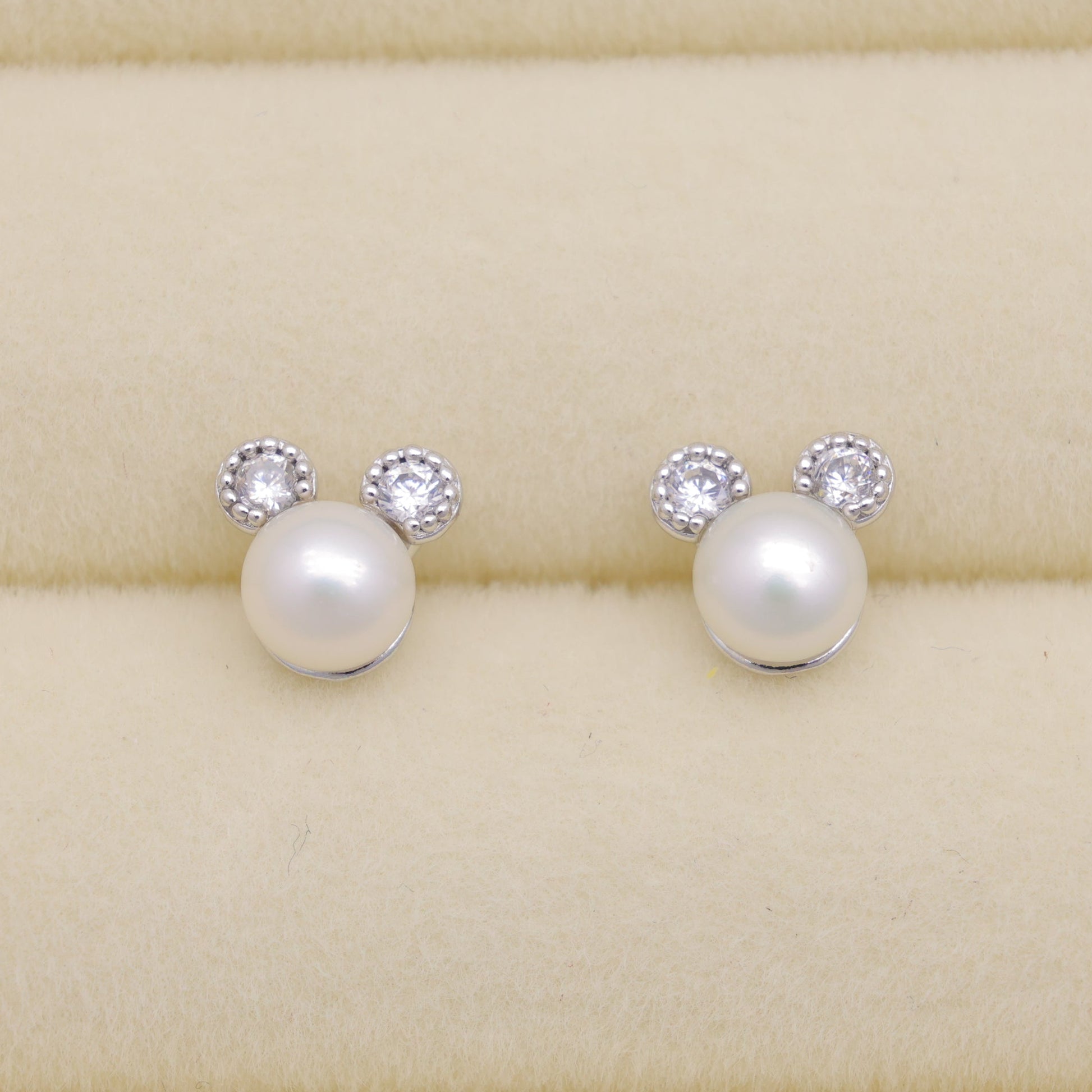 Pearl earrings with small crystals on a beige background
