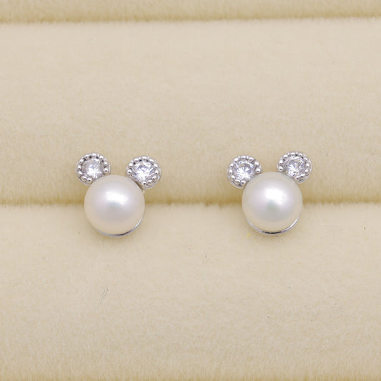 Pearl earrings with small crystals on a beige background