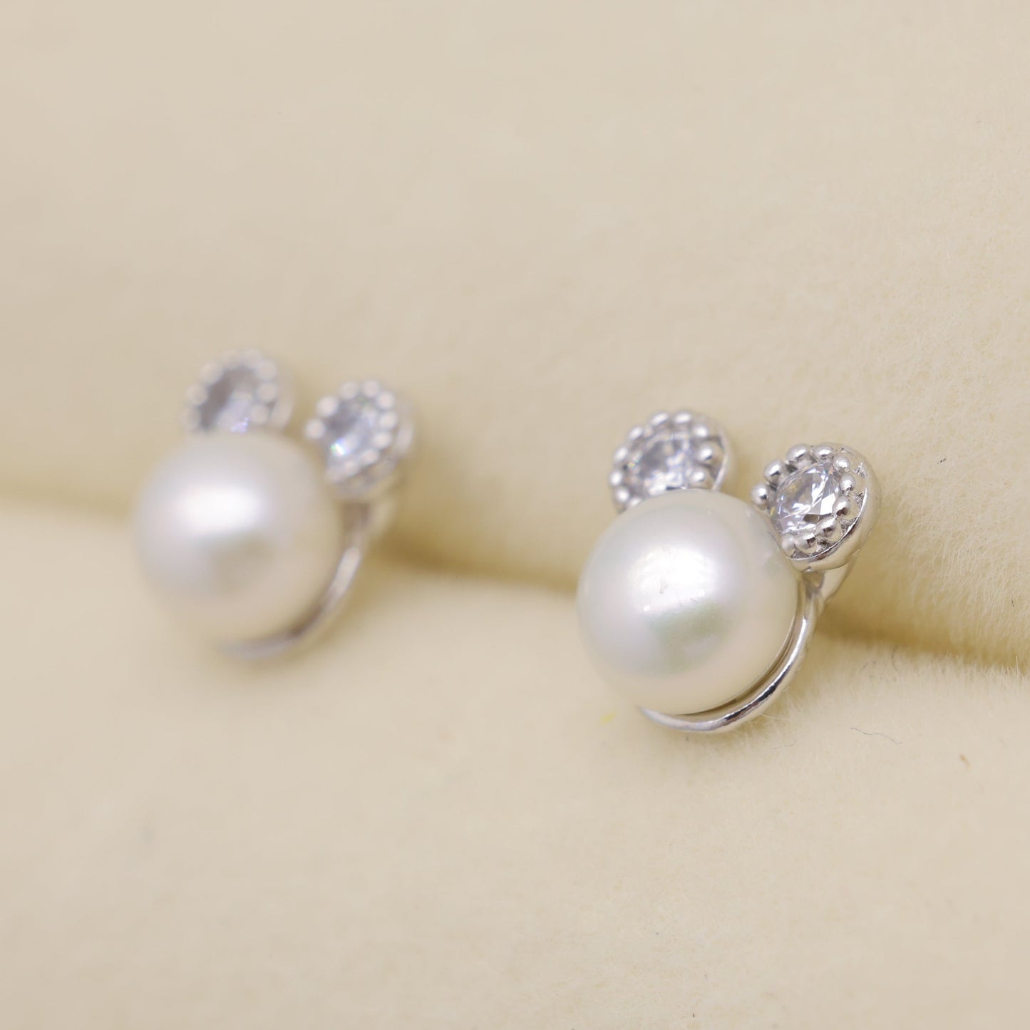 Pearl earrings with small crystals on a beige background