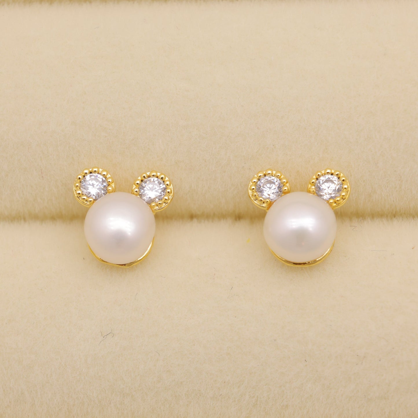 Pearl earrings with gold accents on a beige background