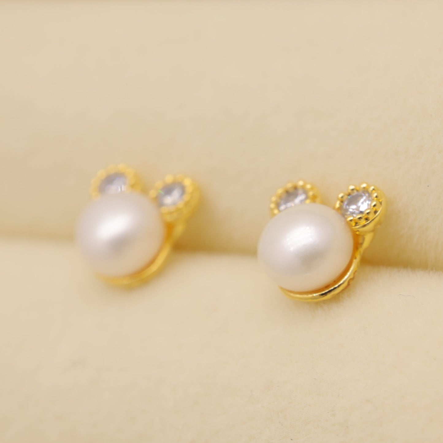 Pearl earrings with gold settings on a beige fabric background