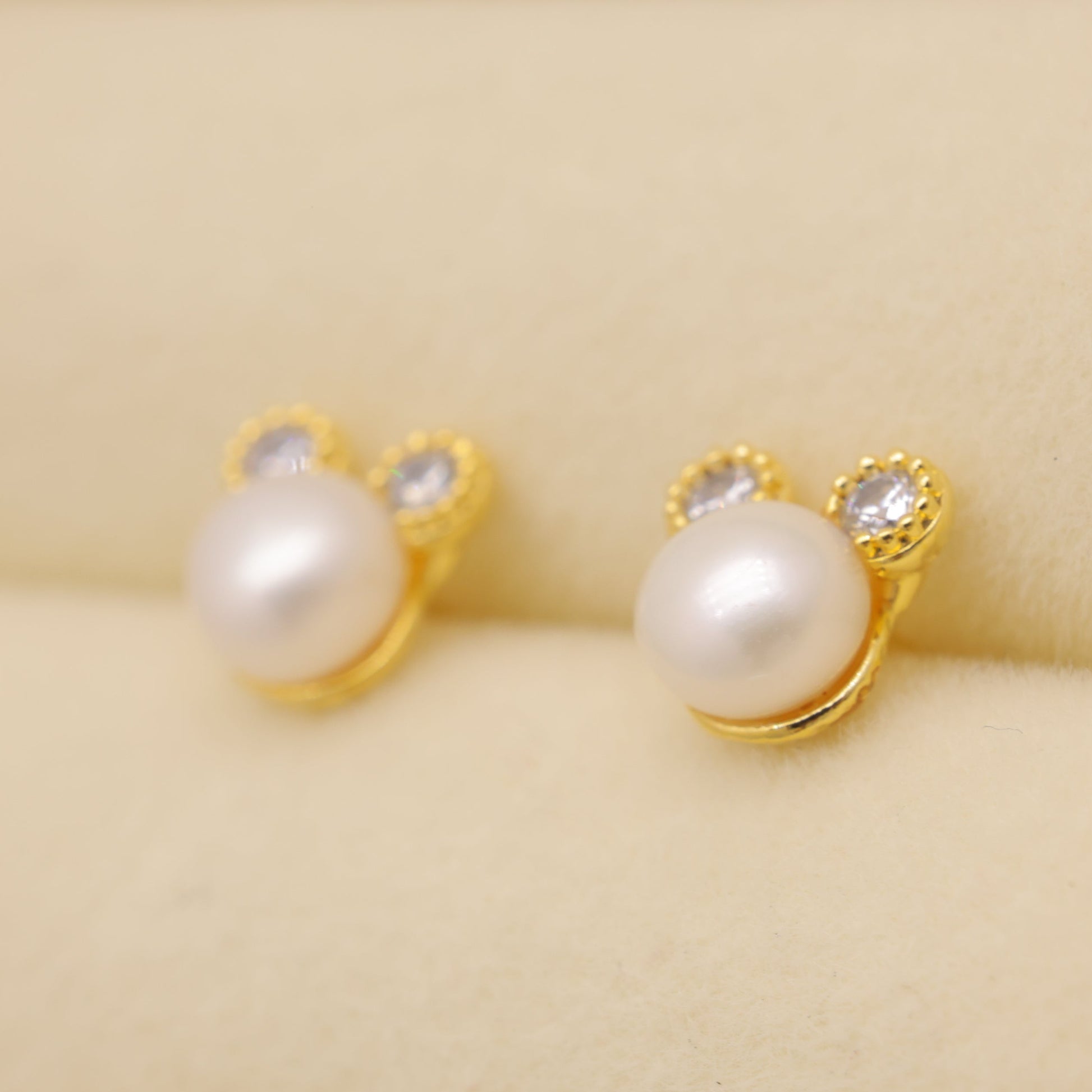 Pearl earrings with gold settings on a beige fabric background
