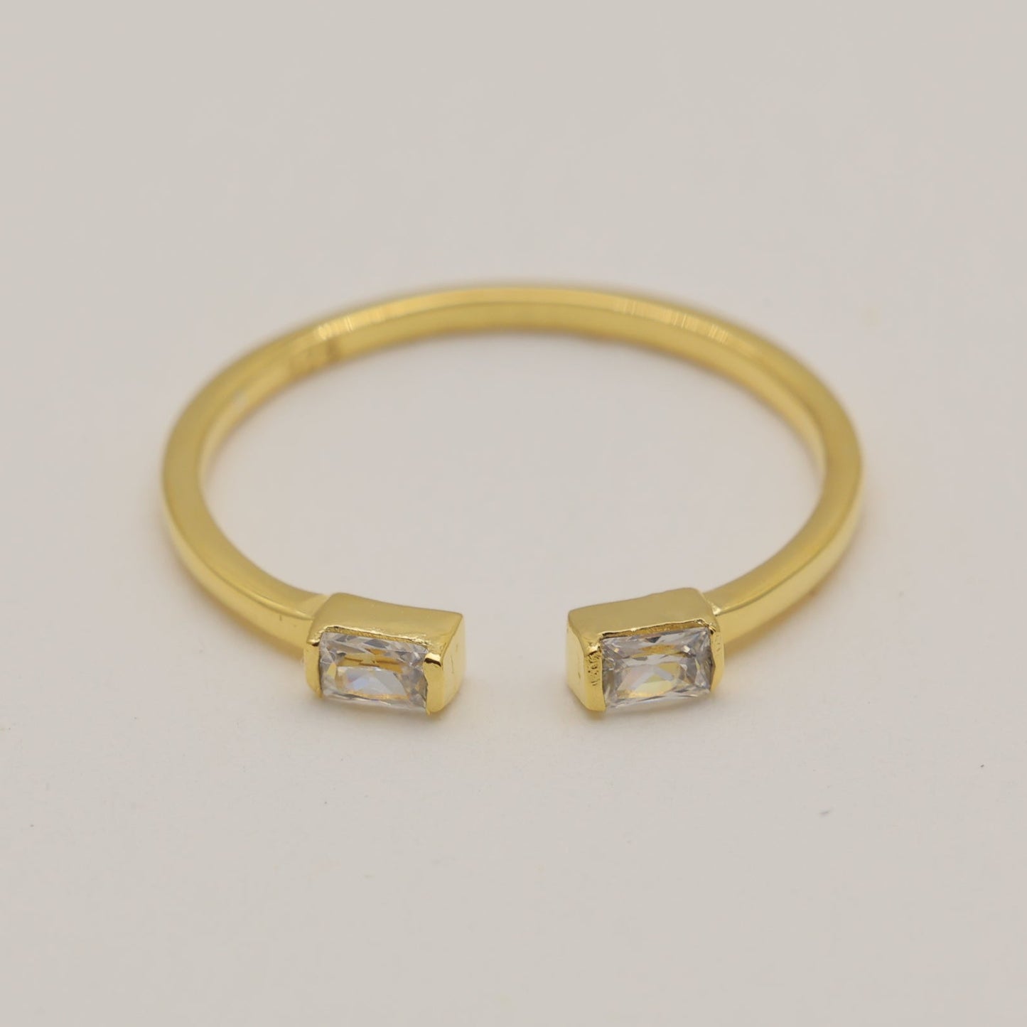 Gold bracelet with square gemstones on a light gray background