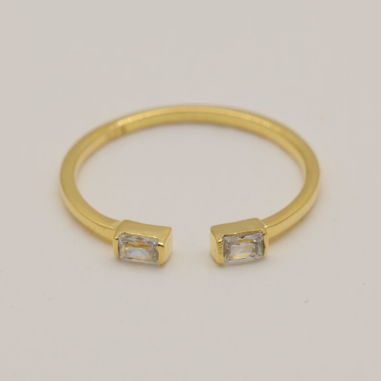 Gold bracelet with square gemstones on a light gray background