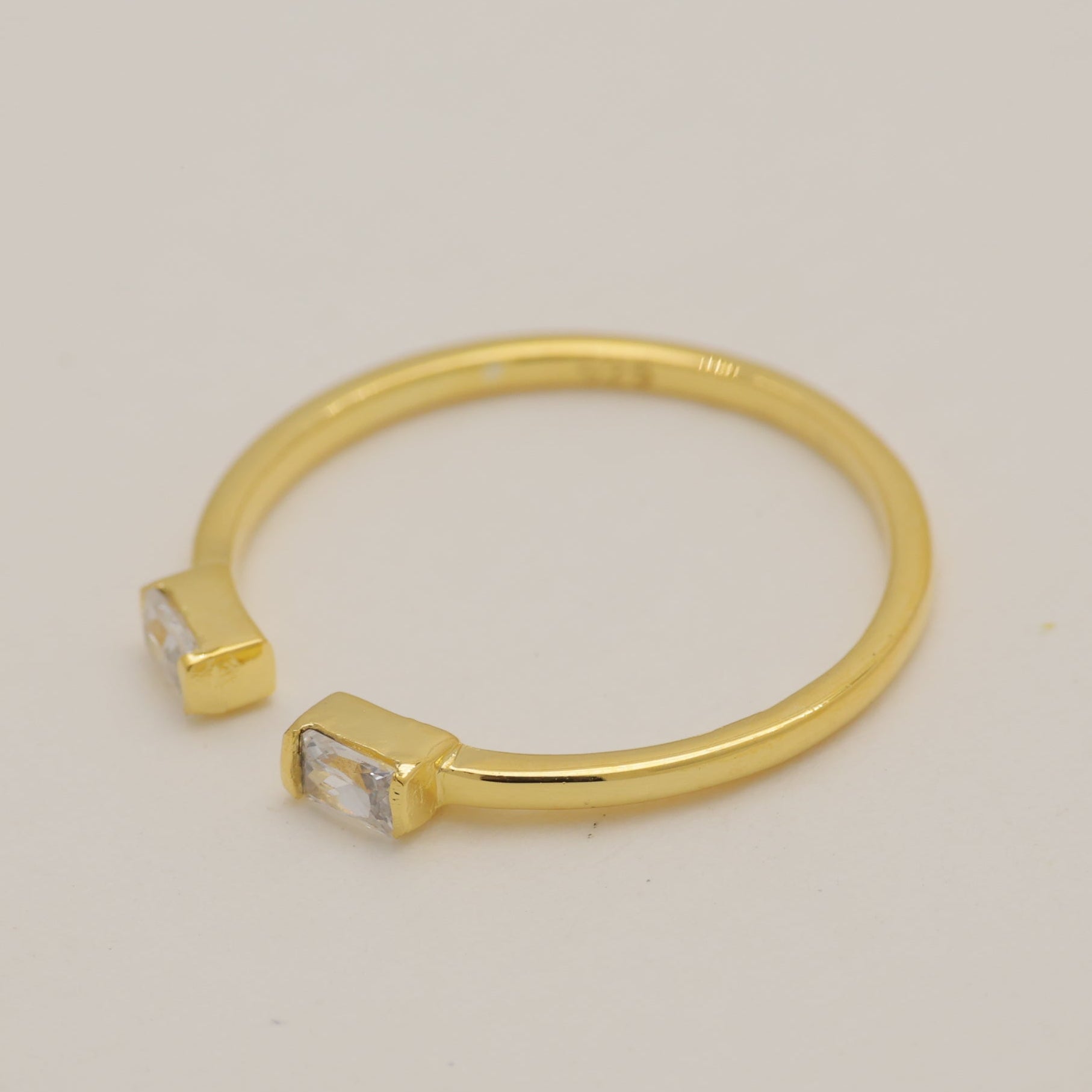 Gold ring with small stones on a light gray background